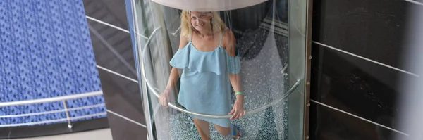 Hermosa mujer sonriente moviéndose en ascensor transparente — Foto de Stock