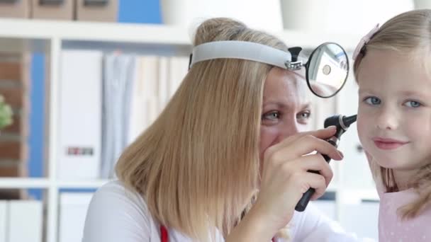 Otorrinolaringólogo lleva a cabo examen médico de la oreja de la niña de cámara lenta película 4k — Vídeo de stock