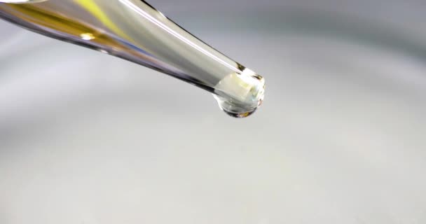 Liquido trasparente con riflessi dorati gocciola da pipetta di vetro film 4k al rallentatore — Video Stock