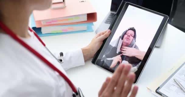 Médico consulta remotamente o paciente on-line enquanto está sentado no local de trabalho câmera lenta filme 4k — Vídeo de Stock