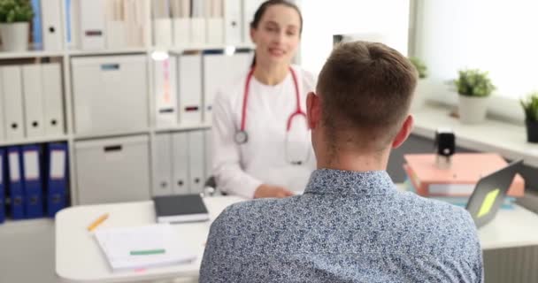 Mujer joven médico hablando con el paciente masculino en el consultorio de la clínica de cámara lenta 4k película — Vídeo de stock