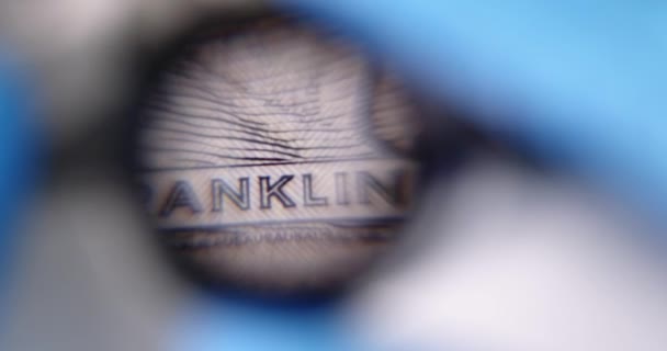 Osoba zkoumá stodolarovou bankovku přes lupu zpomalení 4k film — Stock video