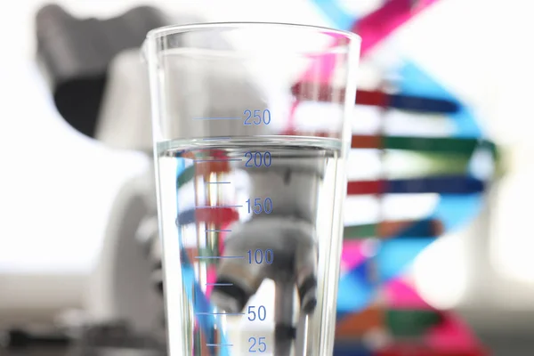 Glas water in de buurt van DNA molecuul mockup en microscoop in laboratorium close-up — Stockfoto