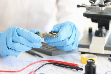 Laboratuvarda yakın planda lastik eldivenlerde mikroçip tutan bilim adamları