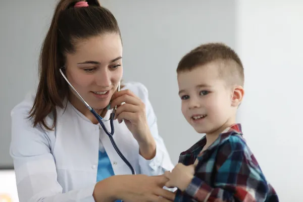 Médico pediatra escuchando al corazón con estetoscopio al niño en la clínica —  Fotos de Stock