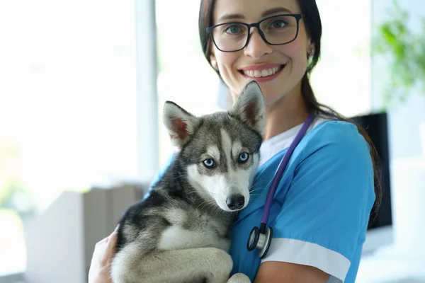 Jeune vétérinaire souriant tient chien dans les bras gros plan — Photo