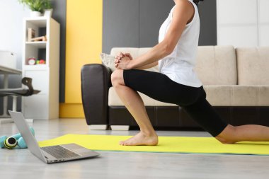 Kadın evde esneme hareketleri yapıyor, online egzersiz yapıyor.