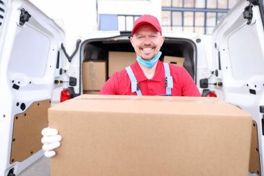 Adamın biri arabadan büyük bir kutu boşaltıyor, kurye servisi.