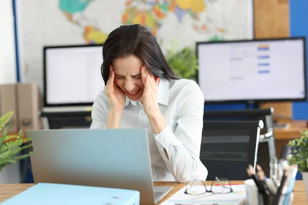 Una mujer en la oficina sufre de dolor de cabeza. —  Fotos de Stock