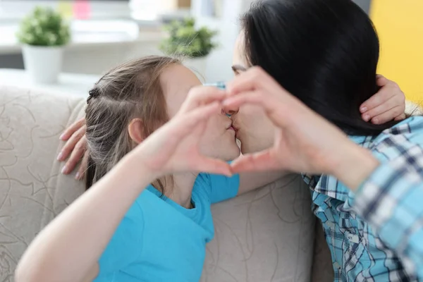 Mutter küsst kleine Tochter, zeigt gemeinsam Herzensgeste — Stockfoto