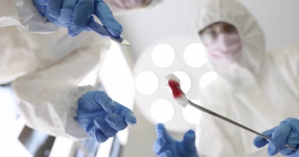 Ärzte in Schutzanzügen bringen Skalpell und Klemme mit Tampon zum Patienten