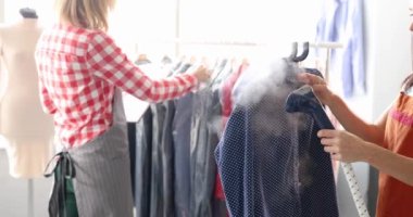 Terzi dükkanında terzi kadın gömleği ütülüyor. Ağır çekimde vapur kullanıyor.
