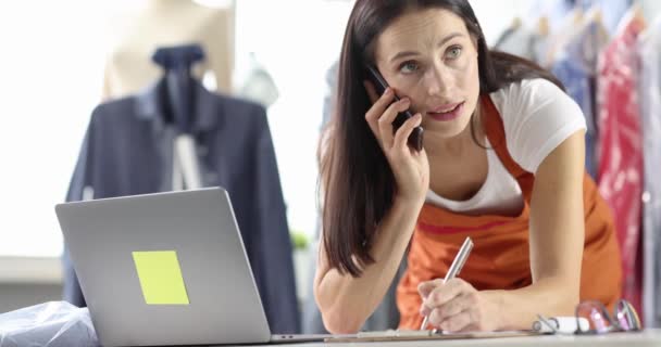 女性管理者が注文書を書き、職場で電話で話す — ストック動画