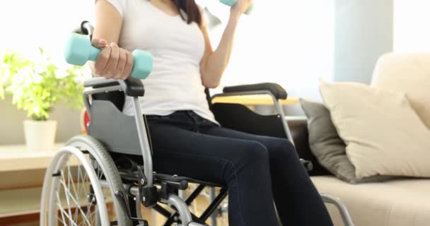 Niepełnosprawna kobieta na wózku inwalidzkim podnoszenie hantli w domu 4k film slow motion — Wideo stockowe