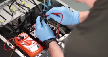 Lastik eldivenler ustası atölyedeki test ediciyle bilgisayar tekniklerini kontrol ediyor.