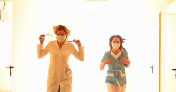 Femmes médecins dans des masques protecteurs coulant dans le couloir de la clinique 4k film ralenti — Video