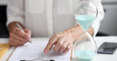 İş kadını ofis 4K filminde kum saati yakınında kontrat imzalıyor.