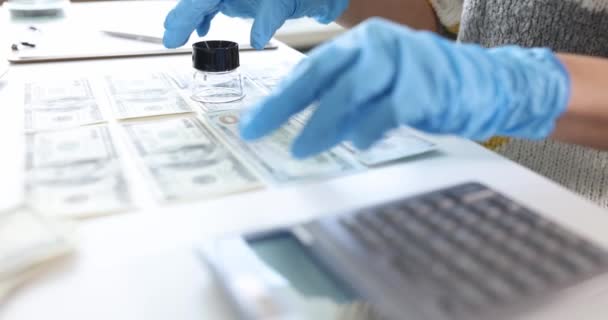 Инспектор в резиновых перчатках смотрит на долларовую купюру с помощью увеличительного стекла 4К фильма замедленной съемки — стоковое видео
