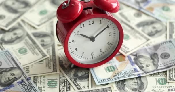 Relógio de alarme vermelho em pé no conjunto de notas de dólar americano closeup filme 4k câmera lenta — Vídeo de Stock