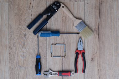 Ahşap arka plandaki inşaat aletlerinden ev figürü oluşturuldu