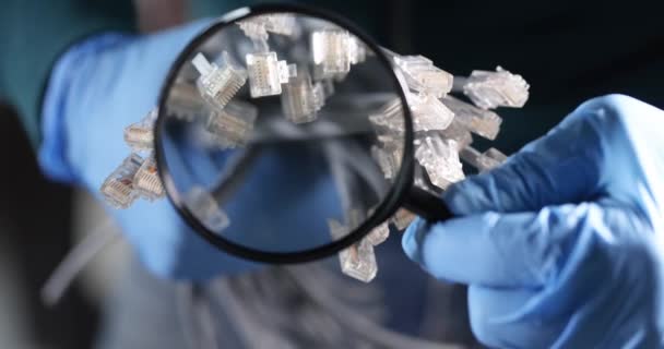 Inżynier w rękawiczkach patrzy przez szkło powiększające na światłowody — Wideo stockowe