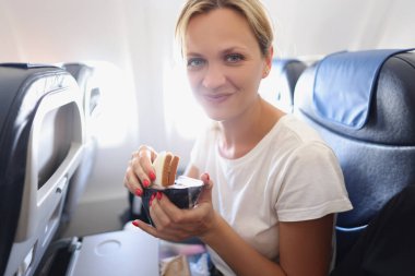 Güzel kadın uçakta leziz sandviçleri açıyor.
