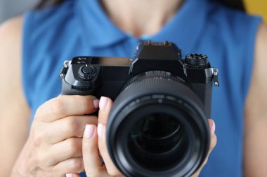 Fotoğraf stüdyosunda elinde fotoğraf makinesi olan mavi elbiseli kadın fotoğrafçı.