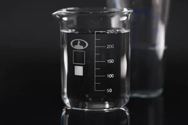 Gros plan de bécher chimique avec de l'eau sur fond noir — Photo