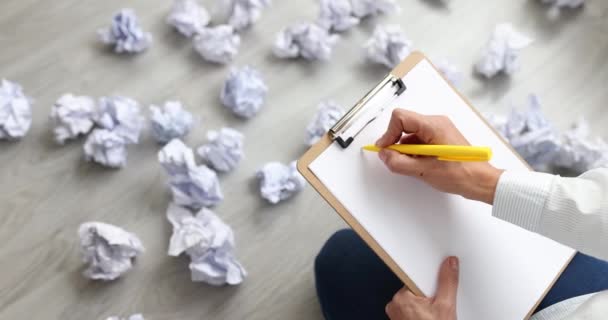 Mulher escrevendo plano de negócios em papel entre documentos amassados espalhados no chão closeup filme 4k câmera lenta — Vídeo de Stock