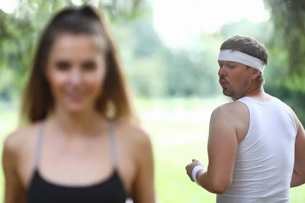 Young man looks at beautiful girl jogging closeup — Stock Photo, Image