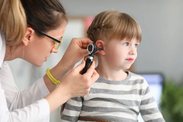 ЛОР-врач проводит физическое обследование уха маленькой девочки — стоковое фото