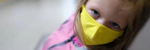 Menina em amarelo máscara médica protetora sentado no corredor do hospital — Fotografia de Stock