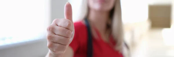 Žena lékař v červené uniformě ukazující palec nahoru detailní up — Stock fotografie
