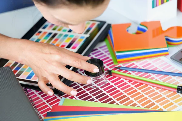 Menina designer olhando através de lupa na paleta de cores — Fotografia de Stock