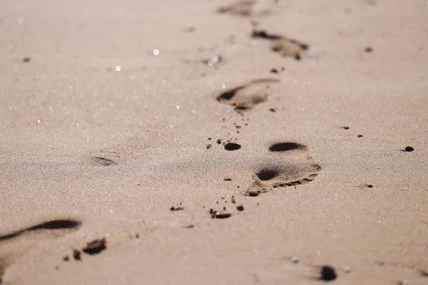 Відбитки людських ніг на золотому пляжному піску — стокове фото