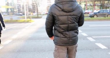 Siyah ceketli adam yaya geçidinde karşıdan karşıya geçiyor.