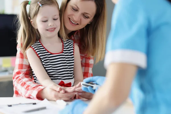 Доктор перевіряє рівень цукру в крові маленької дівчинки, використовуючи цифровий глюкометр в лікарні — стокове фото