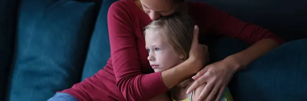 Donna e piccola figlia triste sono seduti sul divano e abbracci — Foto Stock