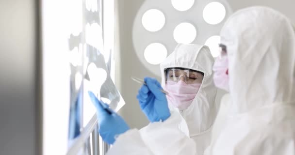 Δύο γιατροί με προστατευτικές στολές και μάσκες εξετάζουν ακτινογραφίες σε εργαστηριακή ταινία αργής κίνησης 4k — Αρχείο Βίντεο
