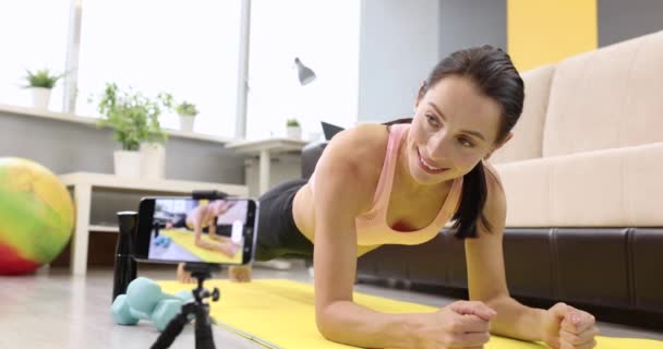 Jeune femme faisant des exercices physiques, debout à bord sur le tapis prenant des photos à la caméra ralenti film 4k — Video