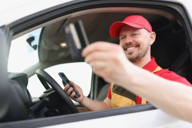 Kredi kartı ve akıllı telefon cihazı tutan neşeli orta yaşlı bir adam.