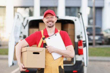 Karton paket ve teslimat makbuzuyla mutlu bir postacı.