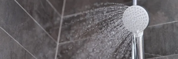 Krypningar av vatten som flyter från duschhuvud i badrum närbild — Stockfoto