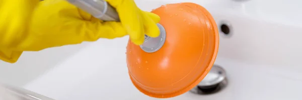 Loodgieter met rubberen handschoenen schoonmaken spoelbak met zuiger in badkamer closeup — Stockfoto