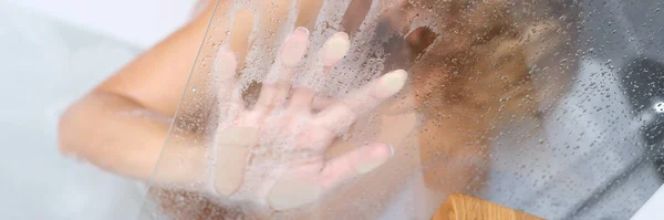 Naakt vrouw zitten in bad en houden haar hand op misted glas closeup — Stockfoto