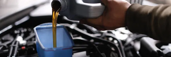 Master repairman pouring motor oil into car engine closeup — Stock Photo, Image