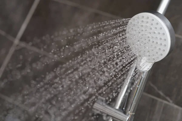 Um fluxo de água está derramando da cabeça do chuveiro — Fotografia de Stock