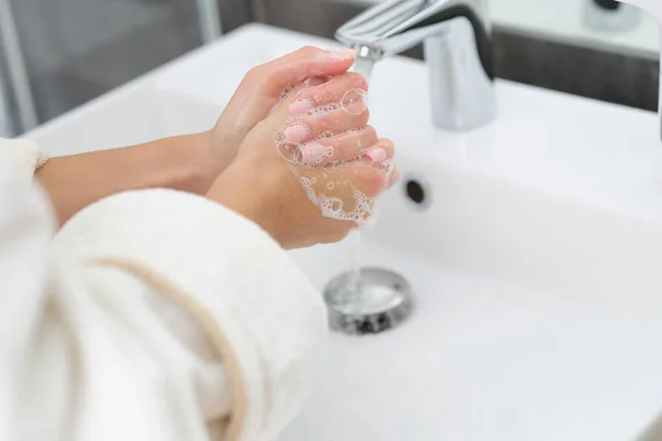 En kvinne som vasker hendene med såpe. – stockfoto