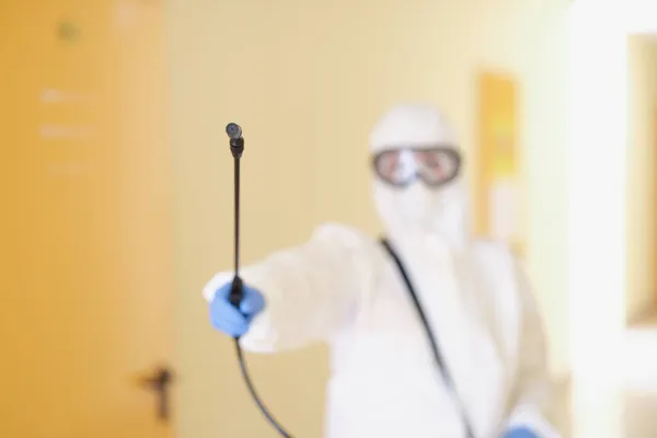 A man in a protective suit holds a sprayer, close-up — Stock Photo, Image