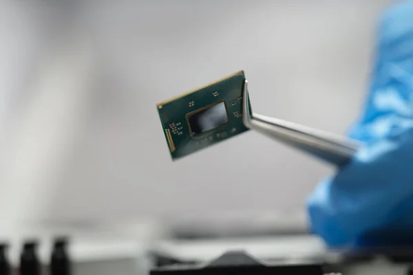 Handschoen handen houden een microchip met pincet, close-up — Stockfoto